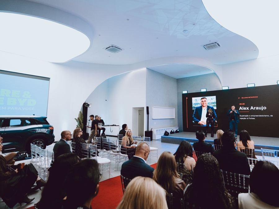 O carro à esquerda e o palco ao fundo, com a sala cheia